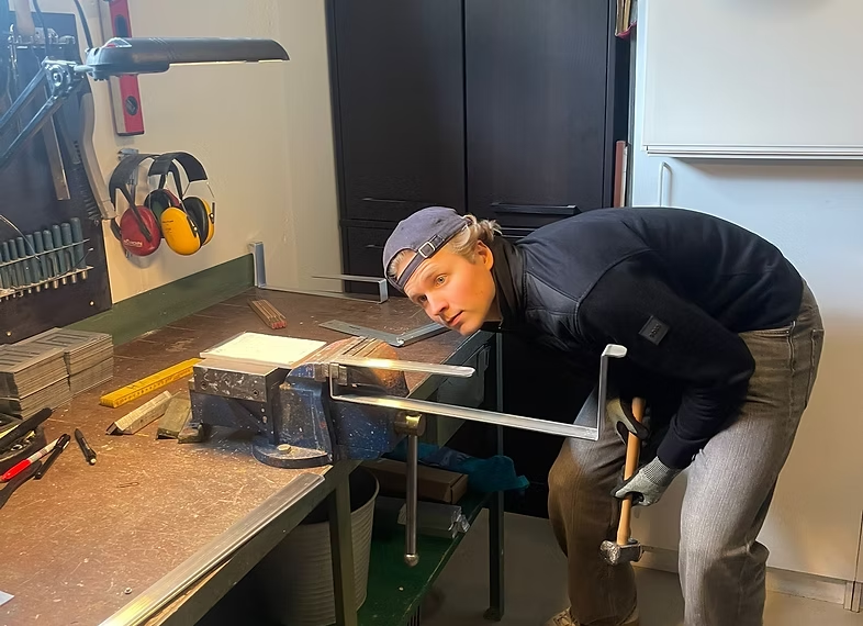 Elias böjer metallprofiler i verkstaden
